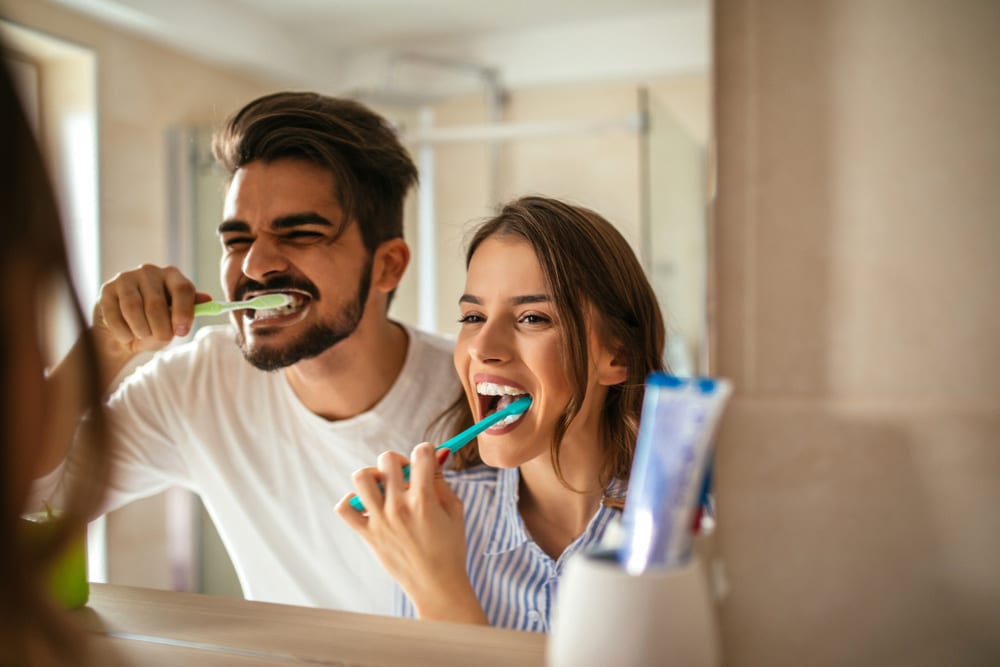 A couple brushes their teeth together following West Richland Family Dental's top 10 ways to take care of your teeth list