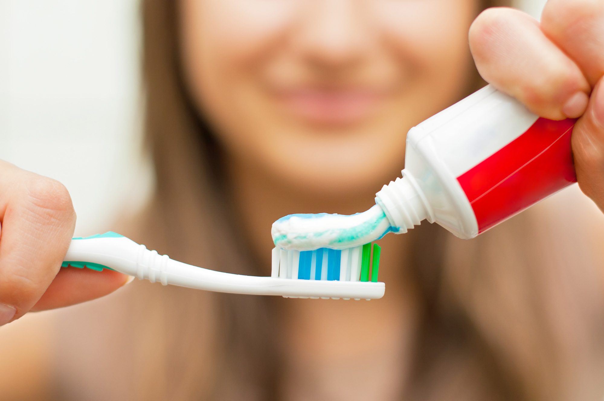 Female patient at Tri-City Dental Care puts high-fluoride toothpaste on her toothbrush.