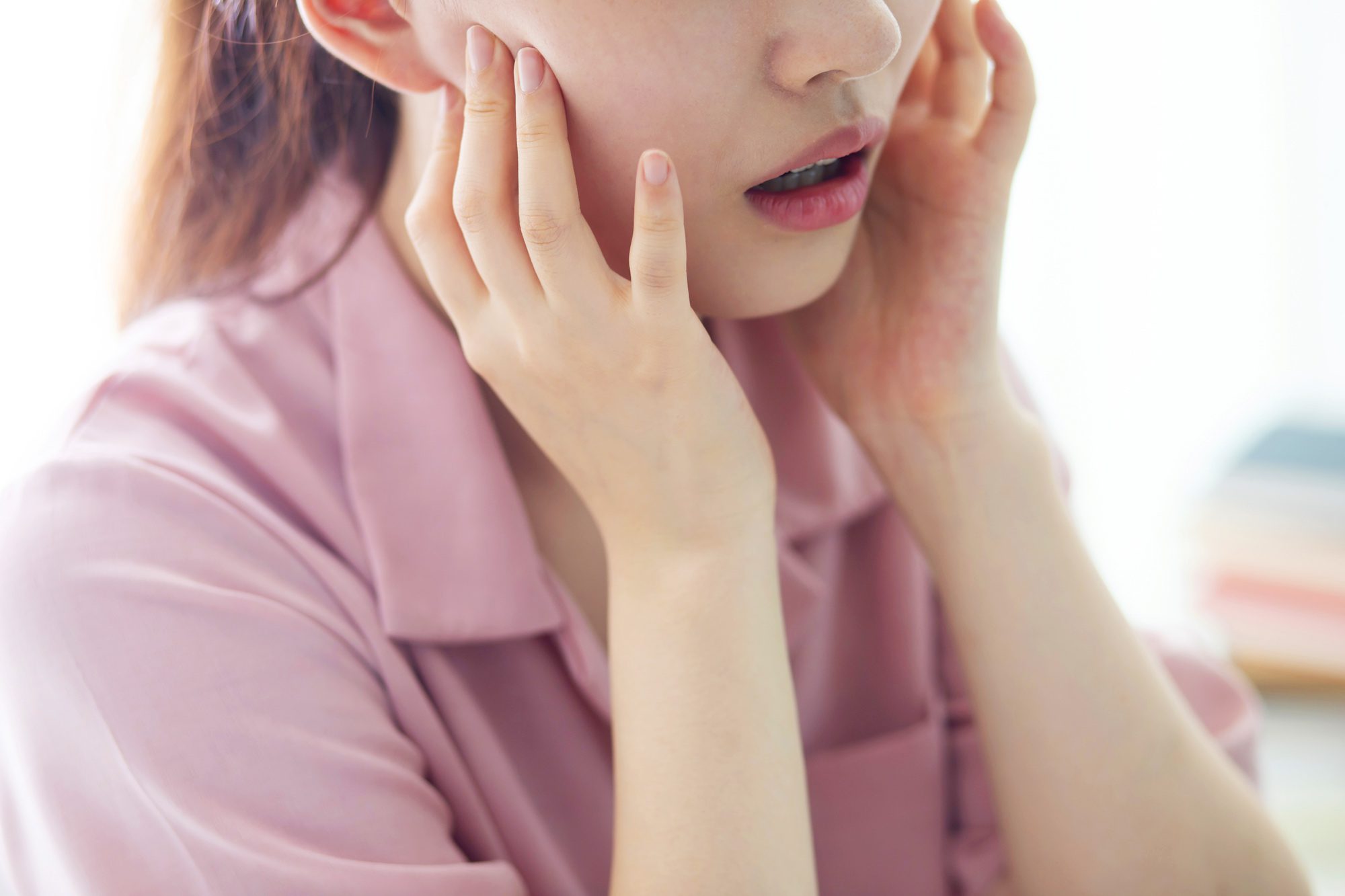 Female patient at West Richland Family Dental holding her mouth as she learns about how oral health affects mental health.